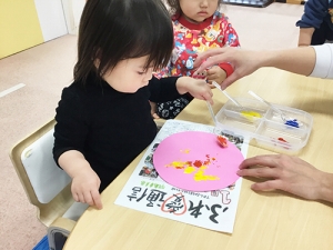 気球の風船の部分にスプーンで絵具を着彩する子ども