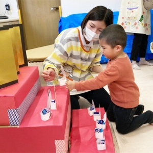 ひな壇を飾り付けする子どもと保育士