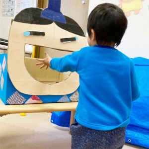 大きな口を開けたお内裏様にボールのあられを入れる子ども