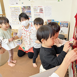 壁面のひな壇にひな人形を飾る子どもたち