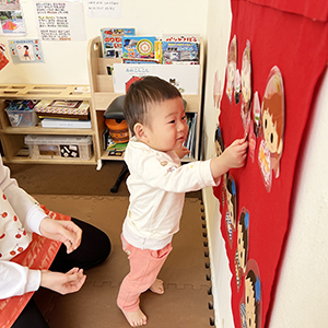 壁面のひな壇にひな人形を飾る子ども