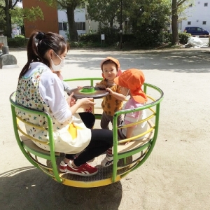 くるくる回る遊具で遊ぶ子どもたちと保育士