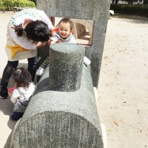 先生と一緒に公園の汽車で遊ぶ子ども