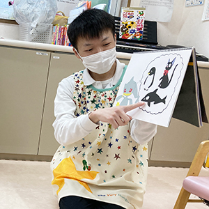 子どもたちに絵を見せる保育士