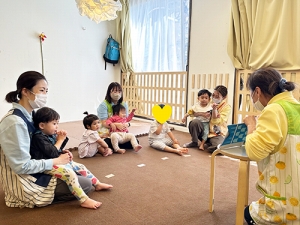 保育士に絵本を読んでもらう子どもたち