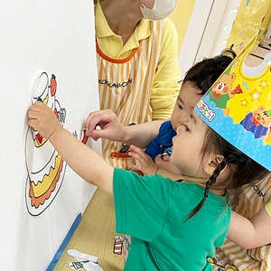 誕生日ケーキに飾り付けをする子どもたち