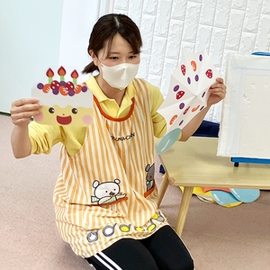 誕生日ケーキの絵の画用紙を見せる保育士