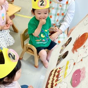 自分の写真や誕生日ケーキが貼られたボードを見て微笑む子どもたち