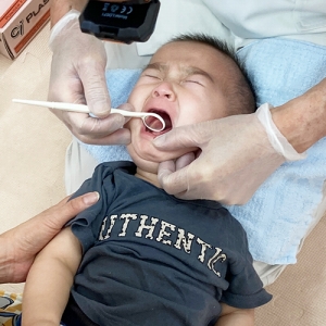 ガマンの表情で大きな口を開け歯科検診を受ける子ども