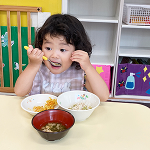スプーンで給食を口に頬張る子ども