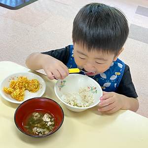 大きな口を開けて夢中で給食を食べる子ども