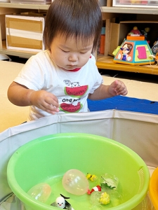おもちゃが閉じ込められた氷を触る子ども