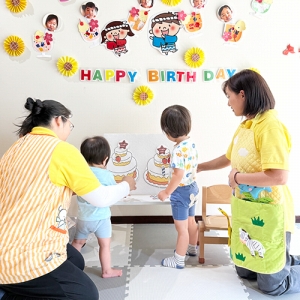 みんなの前でパネルの誕生日ケーキに飾り付けをするお誕生日の子どもたち