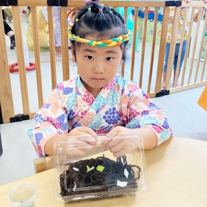 夏祭りイベントで焼きそばのデコレーションをする子ども