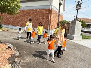 保育士と手を繋いで屋外へ避難する子どもたち