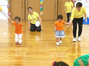 床に置かれた輪から逸れないように進む子どもたち