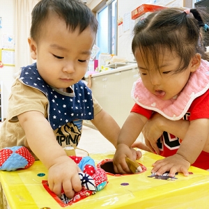 箱の穴に玉を入れる子どもたち