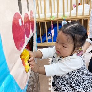 アンパンマンの顔の箱にキャンディーを入れる子ども