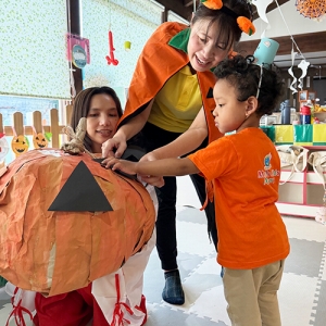 大きなかぼちゃにそっと触れる子どもと保育士