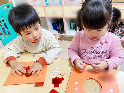 カラーセロハンをカメラの形の画用紙に貼る子どもたち