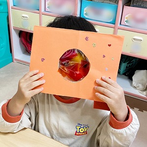 カラーセロハンを貼ったカメラを覗く子ども