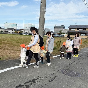 保育士と手を繋いで歩く子どもたち