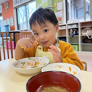 スプーンで給食を食べる子ども