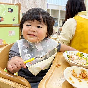 給食を食べて微笑む子ども