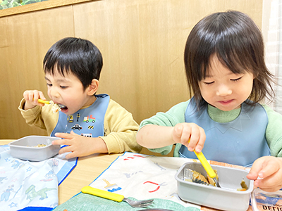 お弁当箱入りの給食をもりもり食べる子どもたち