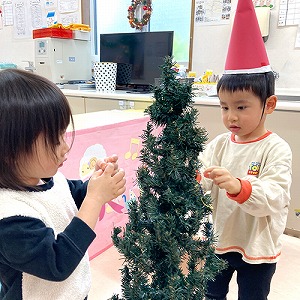 クリスマスツリーに飾り付けをする子どもたち