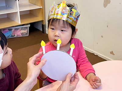 誕生日の王冠を被り、お祝いをしてもらう子ども