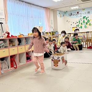 トナカイのお面を被り、ソリを引いて走る子ども