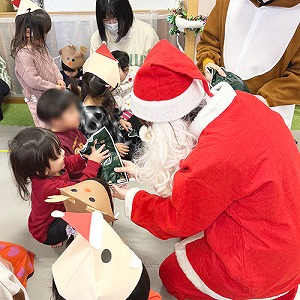 サンタさんからクリスマスプレゼントをもらう子どもたち