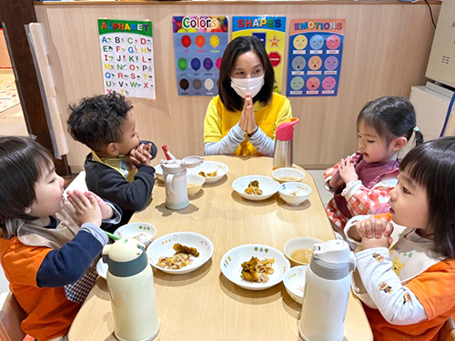 給食の前にいただきますをする子どもたちと先生