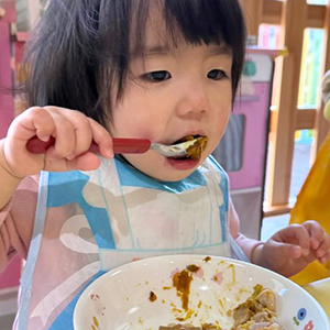 スプーンで給食をほおばる子ども