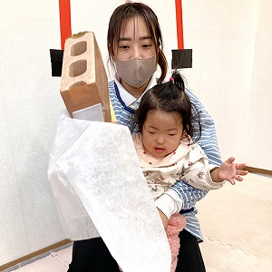 保育士と一緒に餅つきを楽しむ子ども