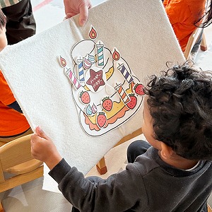 お友だちがデコレーションしたバースデーケーキを持つ子ども