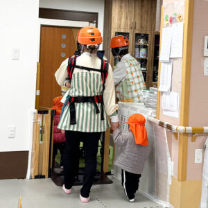 子どもの手を引き避難する保育士