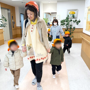 保育士と手を繋いで避難訓練をする子どもたち