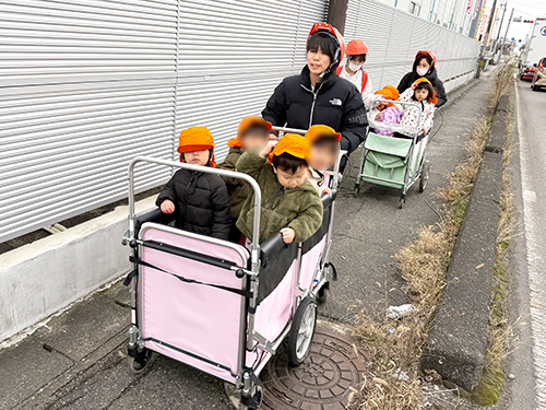 子どもたちを乗せたお散歩カートを押して避難訓練をする保育士たち