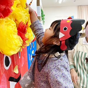 鬼の顔に髪の毛を飾り付けする子ども