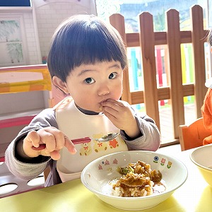 スプーンを持ち、夢中で給食を食べる子ども