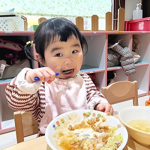 大きな口を開けて給食を食べる子ども