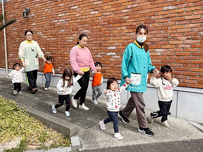 保育士と手をつないで屋外に避難をする子どもたち