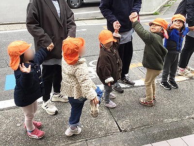 保育士と手を繋いで遠足にでかける子どもたち