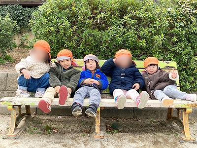 公園のベンチに並んで座る子どもたち