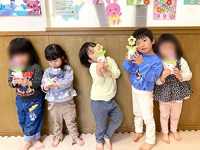 先生からプレゼントされた写真付きお花を持つ卒園児たち