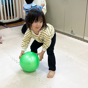 狙いを定めて的に向けてボールを転がす子ども