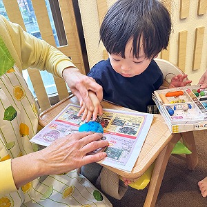 指に絵の具をつけてスタンプのように色をつける子どもたち
