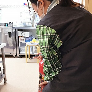 避難訓練で消火器を持つ保育士